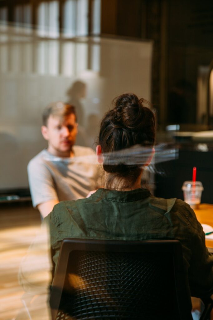 Un home et une femme face à face assis dans un café qui discutent - réunions d'analyse client - études qualitatives